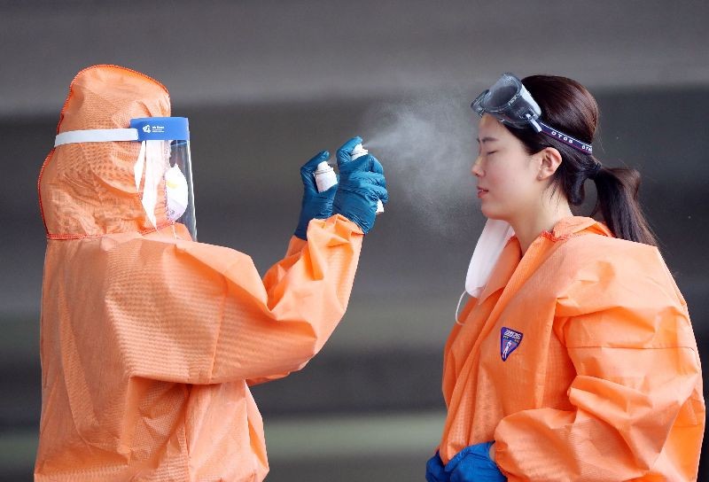 A medical worker in protective gear sprays mist on her colleague during a hot day at an outdoor clinic for coronavirus tests at a public health facility in the southwestern city of Gwangju, South Korea, 05 June 2020. (Photo by Yonhap/EPA/EFE)